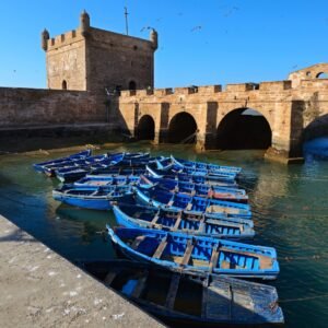Essaouira kikötője kék halászhajókkal és a Castelo Real erőddel, Marokkó atlanti partján